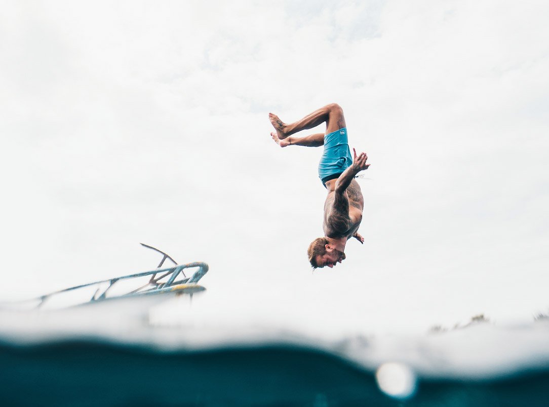 foto de uma homem pulando no mar de um barco